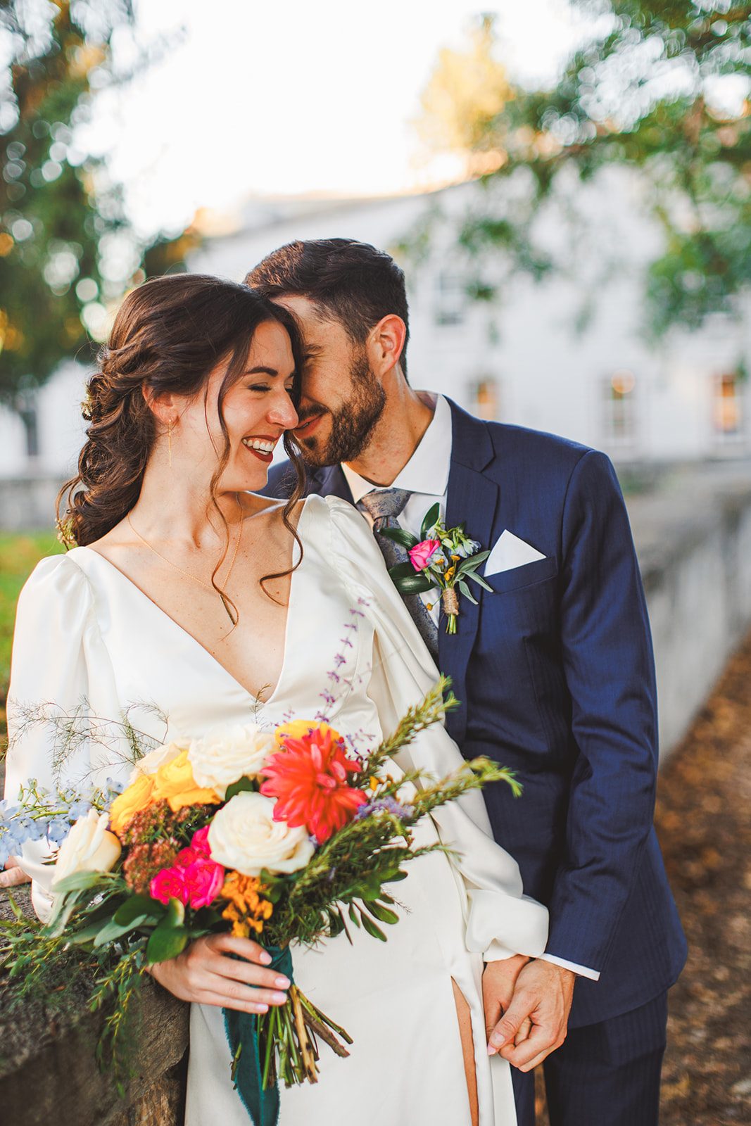 A couple forehead to forehead in soft golden light, the bride laughing with her eyes closed