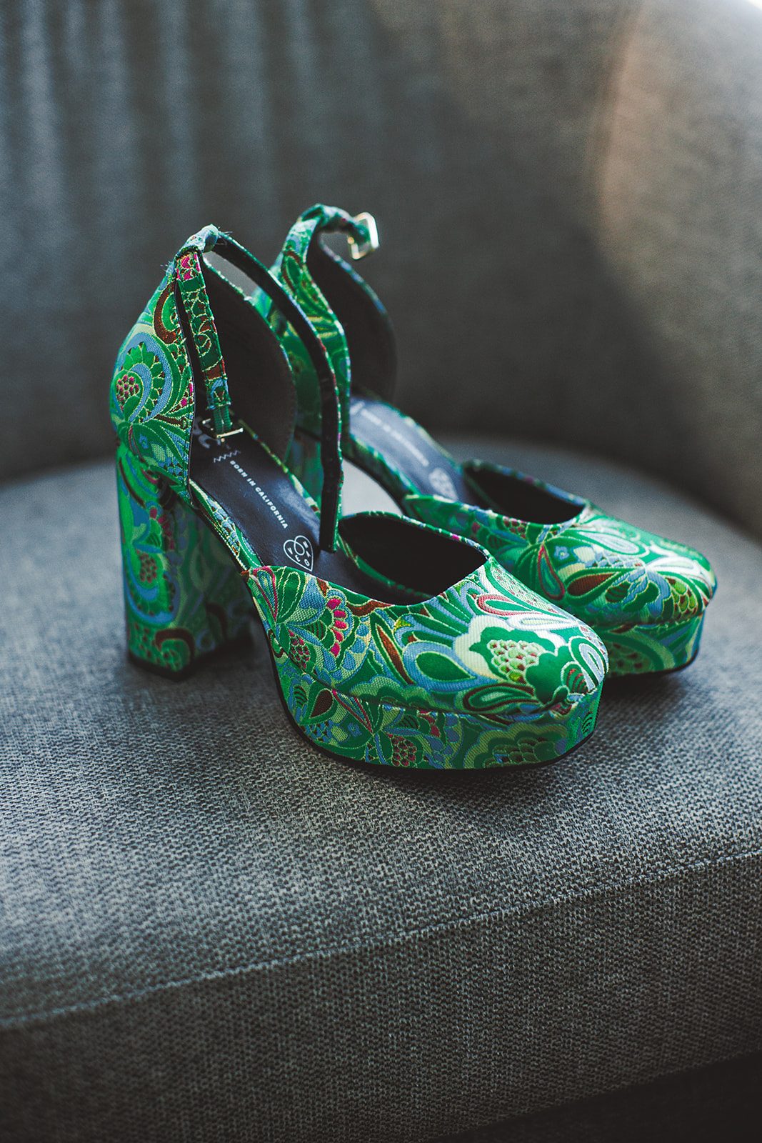 Andrea's emerald green platform heels beside her bouquet of ranunculus, roses, and dahlias