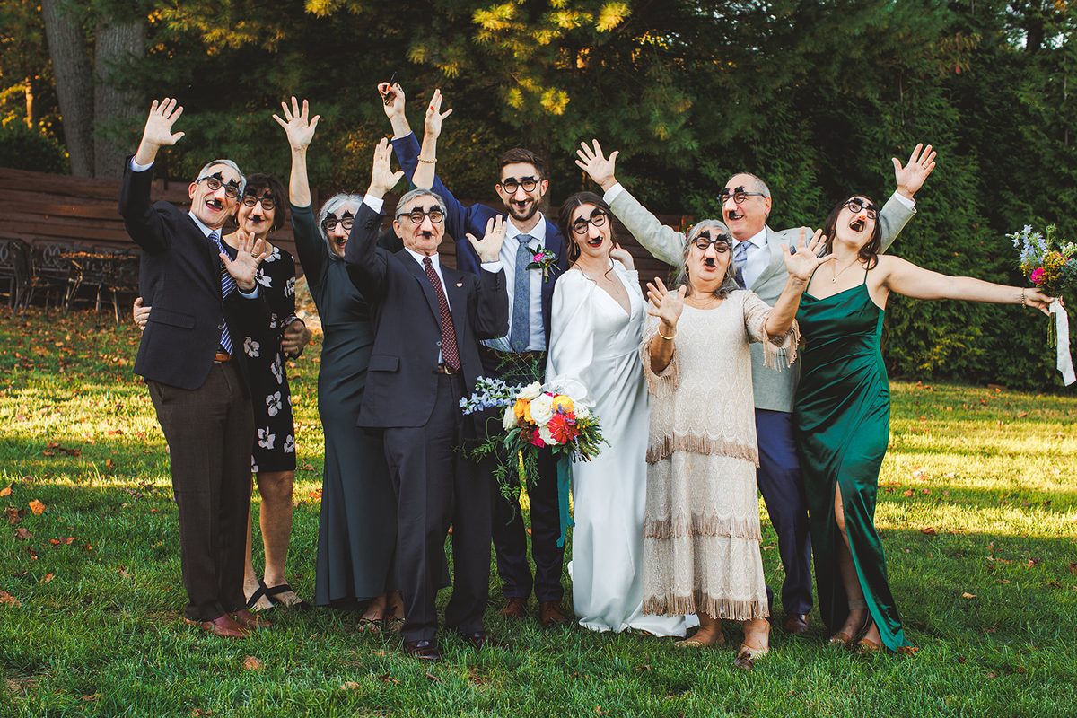 The immediate family in Groucho-glasses disguises with their arms flung wide, laughing
