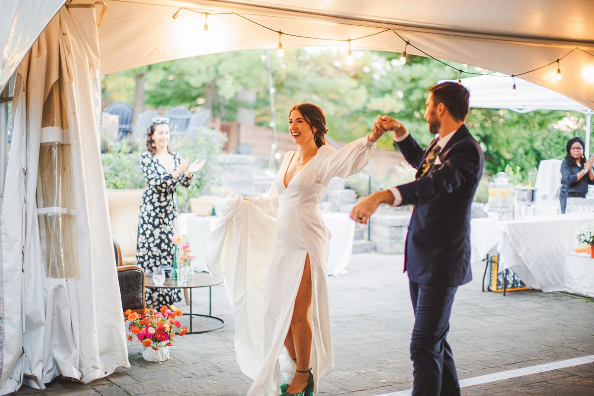 Patrick twirling Andrea under the string lights at the edge of the tent as guests applaud