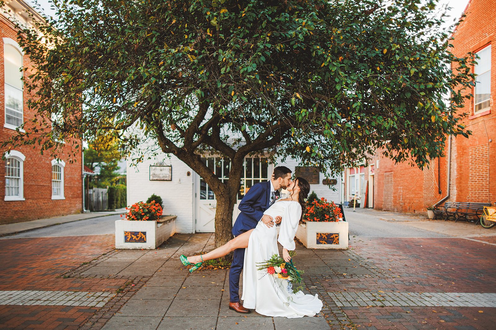 Patrick dipping Andrea into a kiss beneath the great spreading tree on a brick corner in Shepherdstown, her green heel kicked up and her bouquet trailing toward the sidewalk