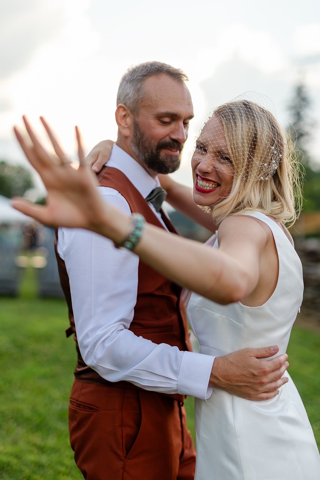 Annie laughing with her arm flung toward the camera as Thomas holds her close on the lawn
