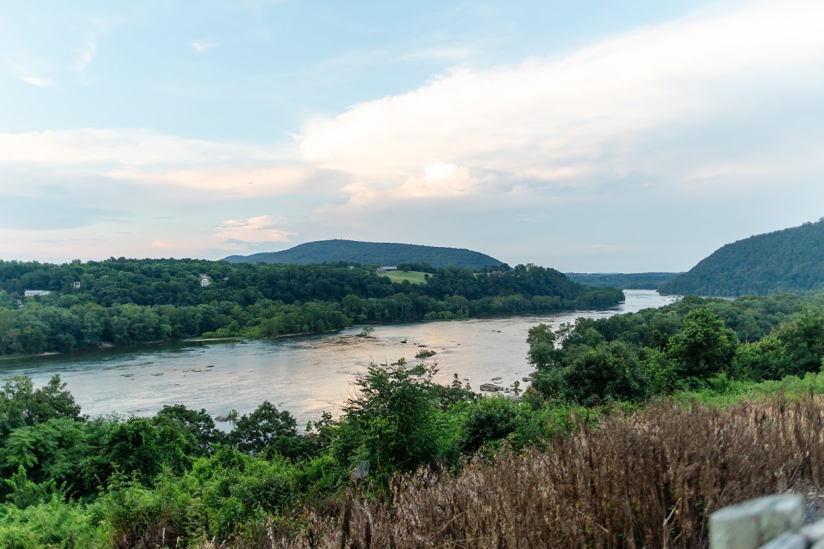 The Potomac winding through the wooded water gap at Harpers Ferry under a soft evening sky