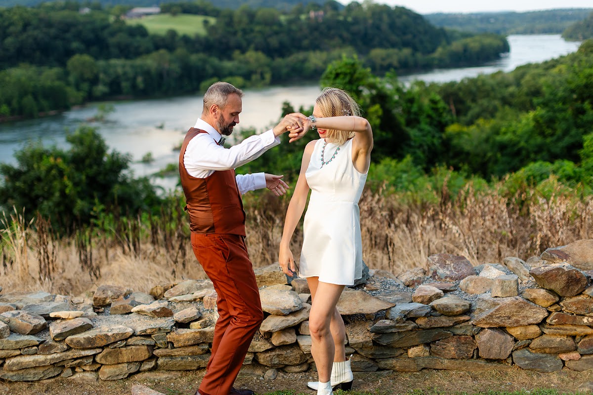 Thomas leading Annie by the hand in a dance beside the low stone wall, the Potomac and wooded hills rolling out below
