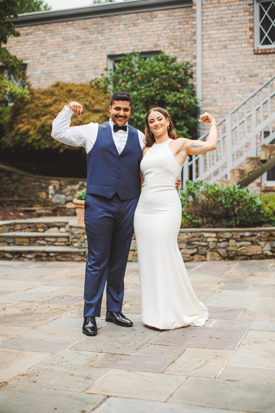 Bailey and Youssef flexing side by side on the garden patio, her arm tattoo reading Confidence, both grinning