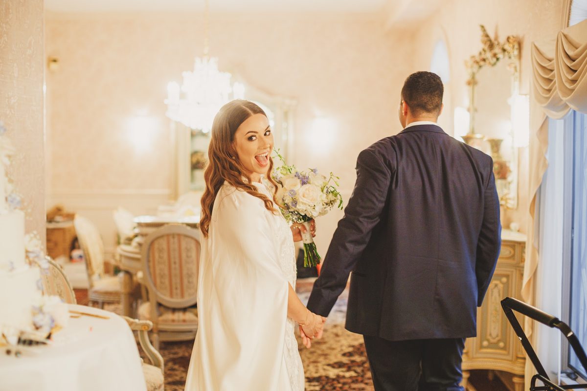 Bailey glancing back at the camera open-mouthed with delight as she leads Youssef by the hand out of the ceremony room