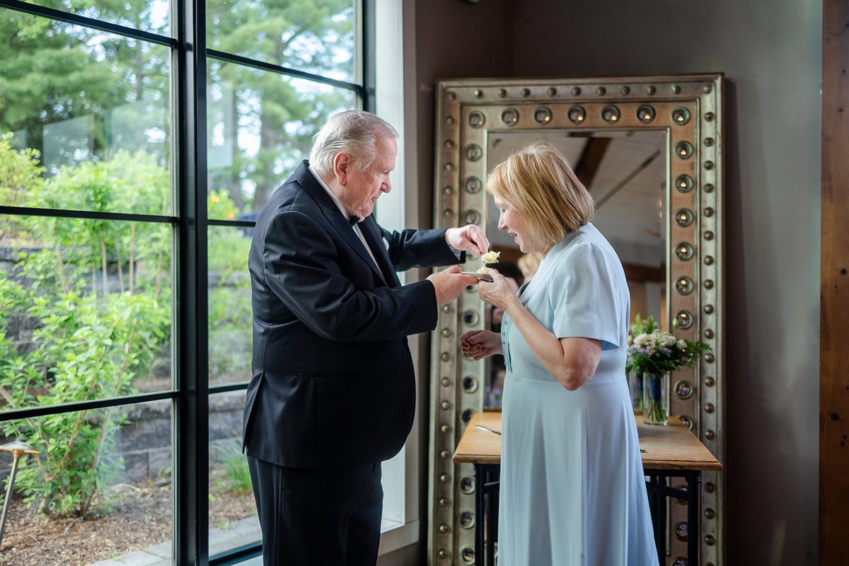 Mary laughing as Mark offers her the first bite of wedding cake