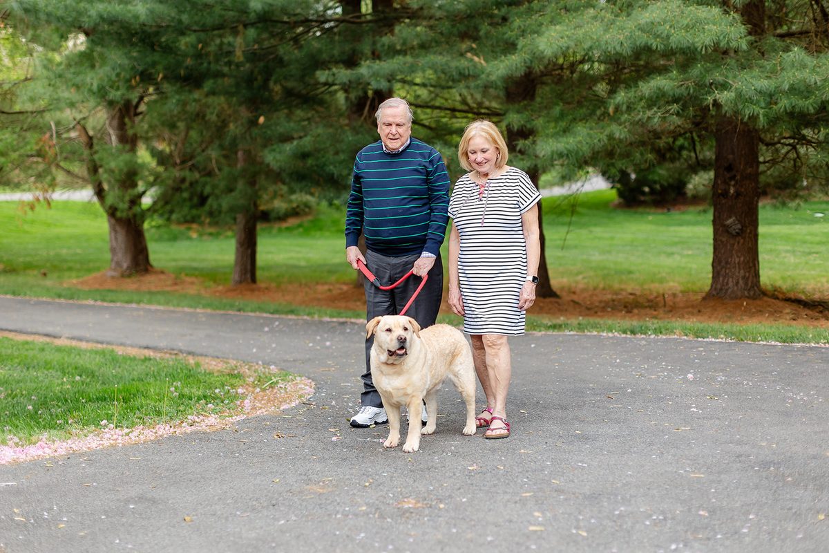 Mary and Mark walking down the lane hand in hand with a yellow lab on a leash between them