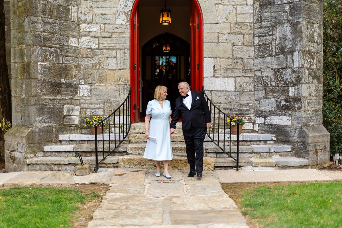 Mary and Mark waving from the red arched doorway of the church tower