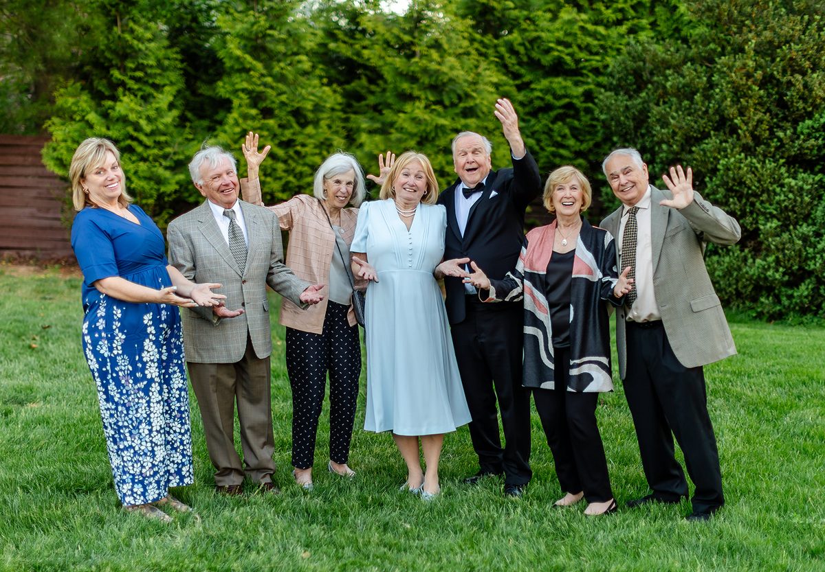 A row of guests on the Bavarian Inn lawn waving and laughing in the golden evening light
