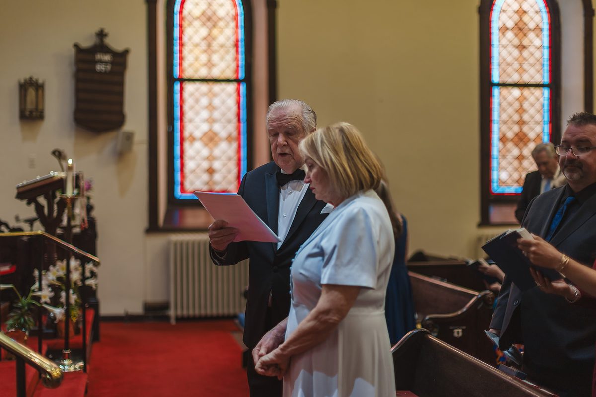 Mary and Mark singing together from a shared hymn sheet at the front of the church