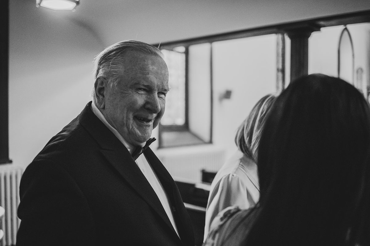 Black and white portrait of Mark laughing in his tuxedo and bow tie before the ceremony
