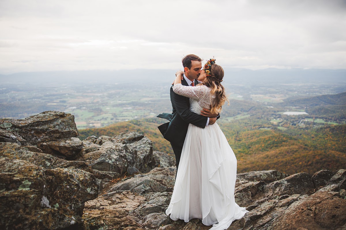 A couple kissing on a rocky Shenandoah overlook with the valley spread out far below them
