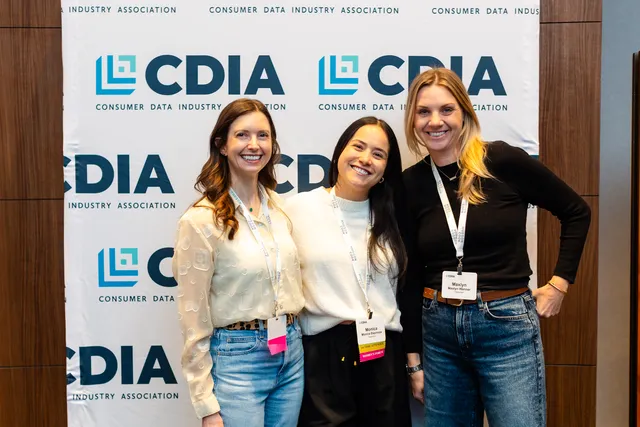 Three smiling guests pose together in front of a Consumer Data Industry Association step-and-repeat backdrop.