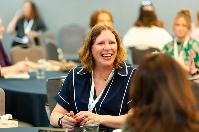 Attendee mid-laugh at a round table.