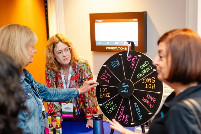 Attendees spinning a prize wheel at a sponsor table.
