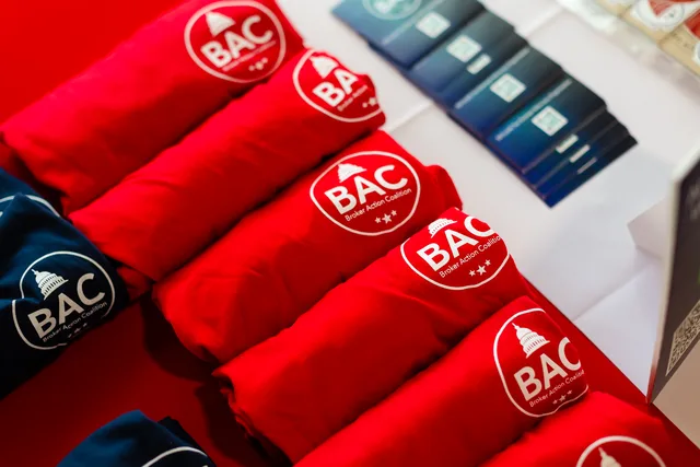 Stacked red BAC branded shirts.