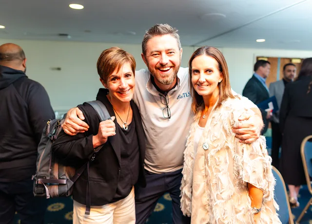 Three attendees in a warm group hug.