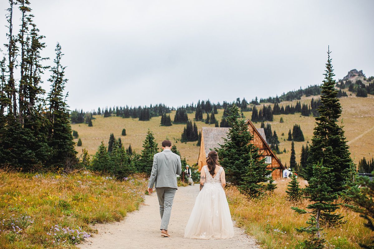 A couple walking away up a mountain path toward the peak, seen from behind