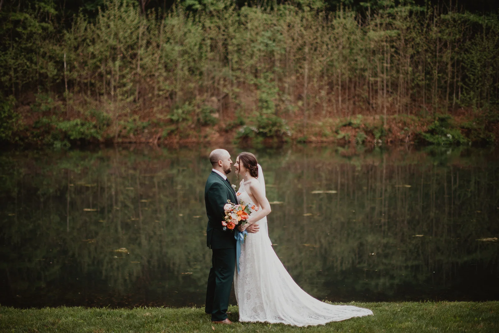 Emily and Garrett standing together by the lake at Coolfont Resort