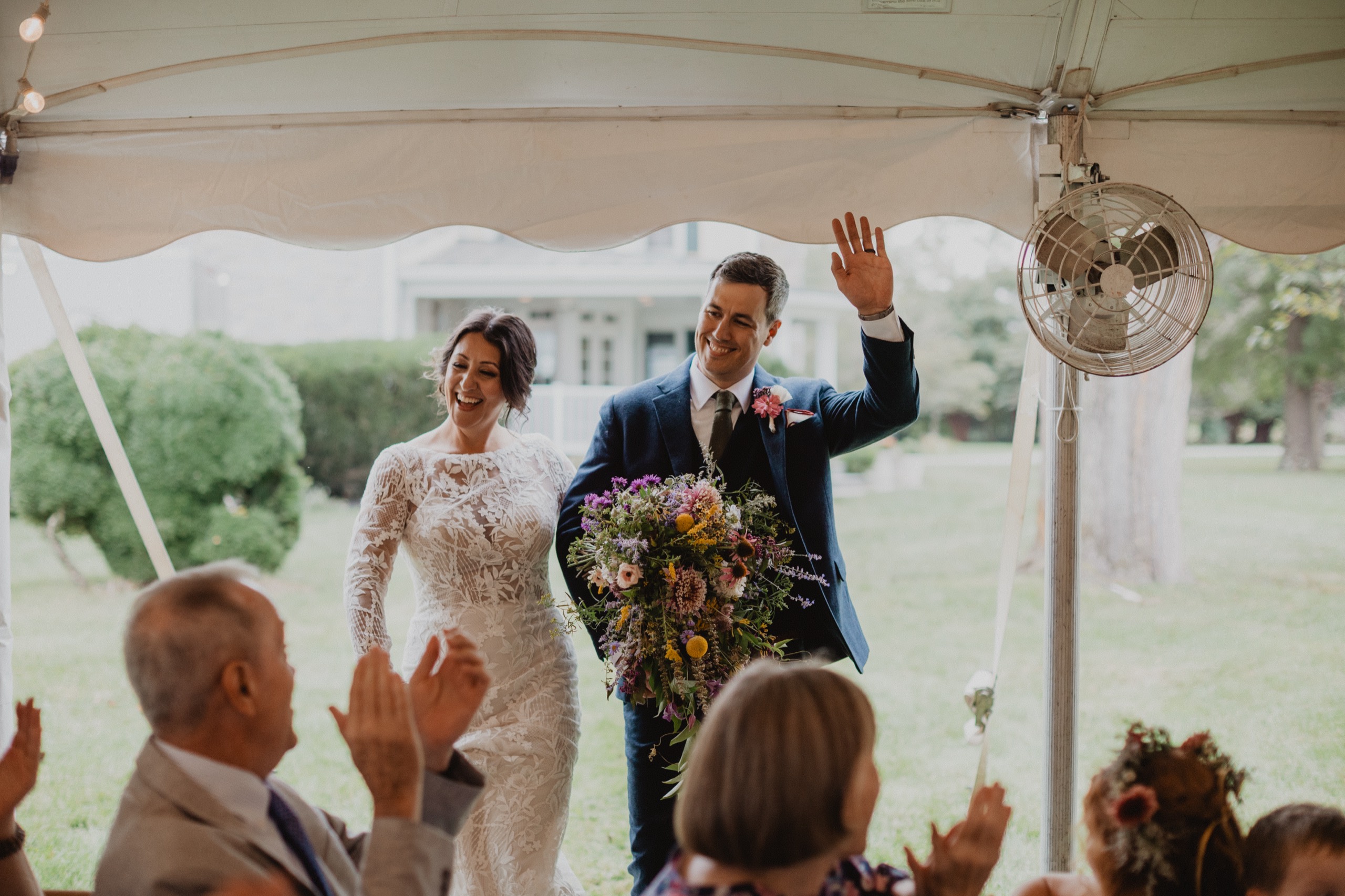 Alyssa and John walking into their reception to applause at the Hawthorn Inn