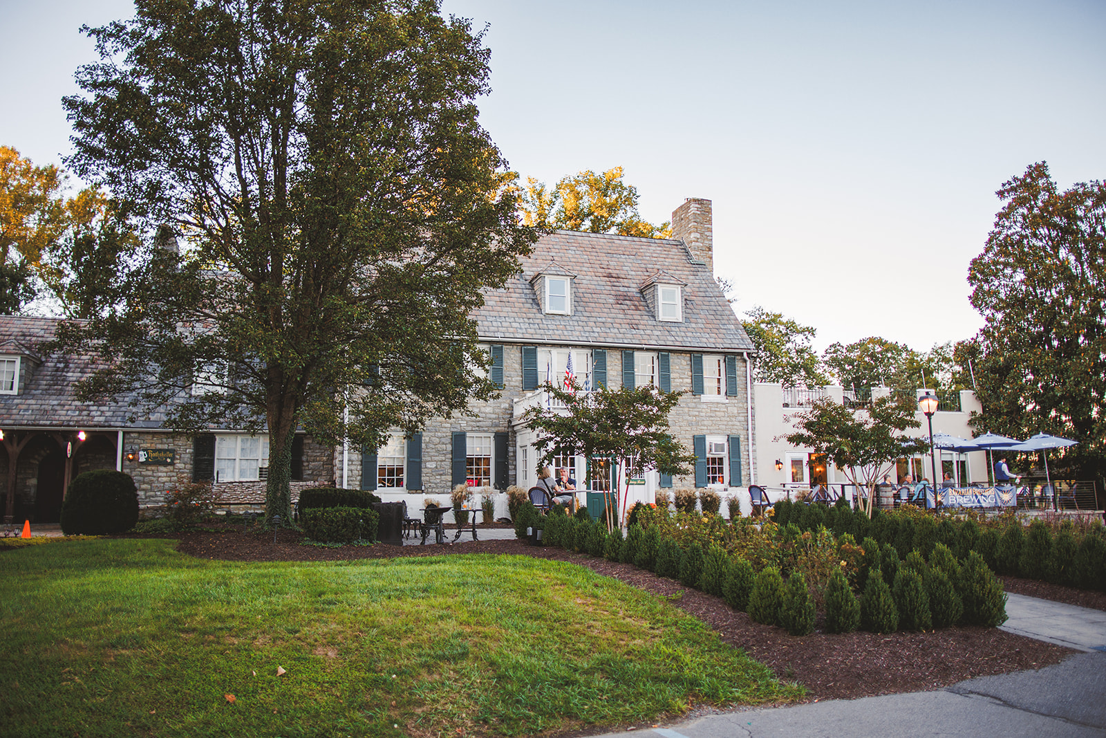The stone main house of the Bavarian Inn in Shepherdstown at dusk, lawn and boxwoods in front