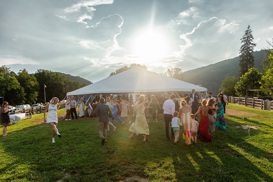 Guests dancing on the lawn at Harpers Ferry Brewing as the sun drops behind the reception tent and the ridge