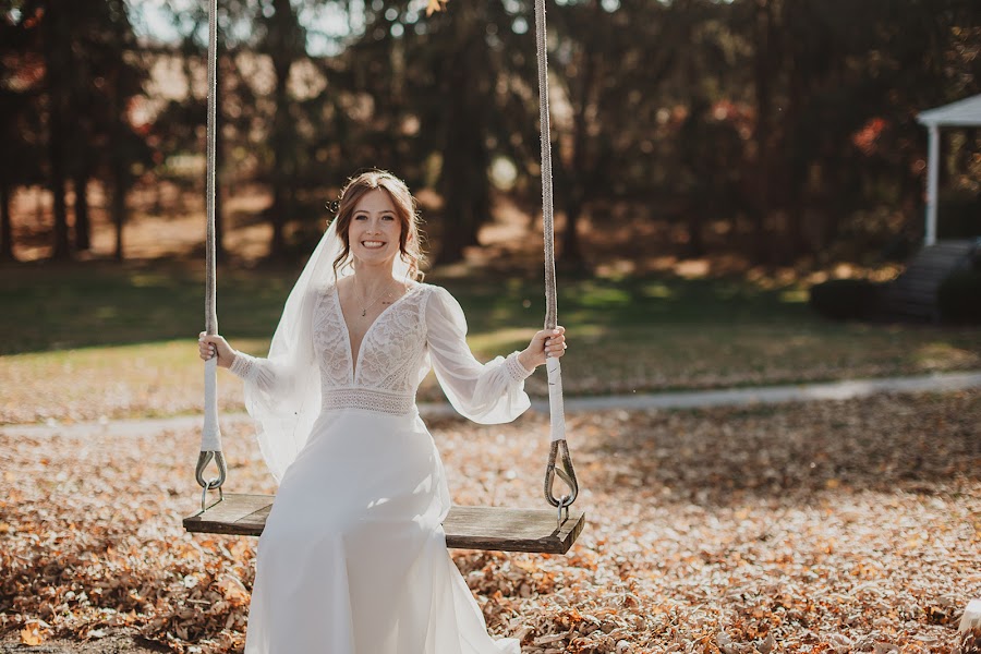 Delaney on a wooden tree swing in golden light, leaves scattered across the ground behind her