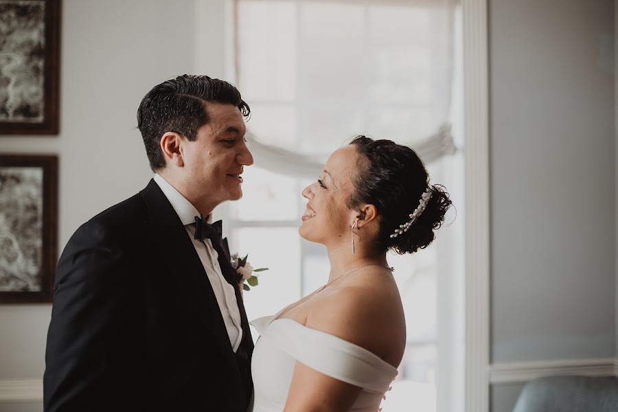 Jessica and Nicholas laughing face to face against a bright window at the Morrison House