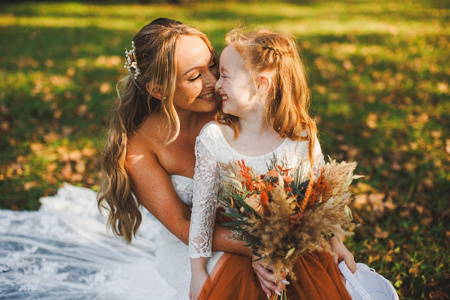 Maggie nose to nose with the flower girl on her train at Fox Haven Farm, both laughing in golden light