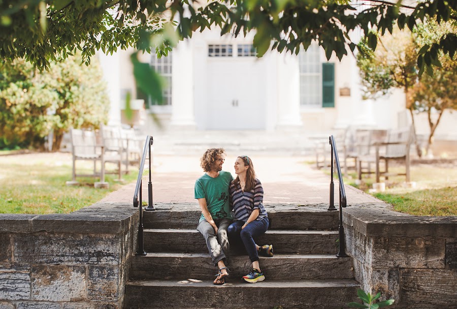 Meredith and John small on the stone steps beneath a canopy of summer leaves